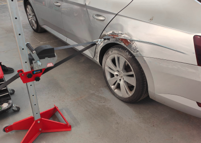 Silver car having dent being pulled out