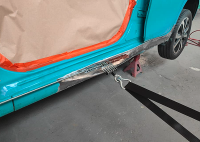 Blue car having dent being pulled out